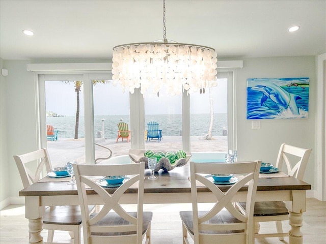 dining room with a water view, a chandelier, and light hardwood / wood-style floors