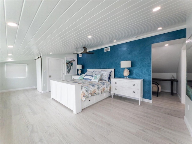 bedroom featuring a barn door and light wood-type flooring