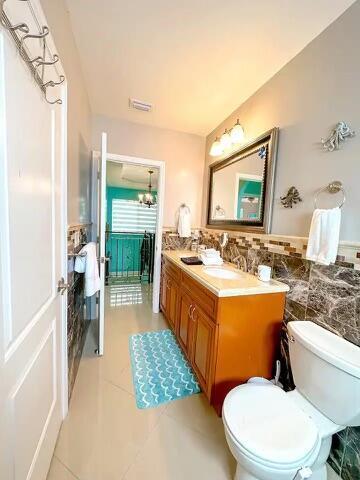 bathroom featuring tile walls, vanity, tile patterned floors, and toilet