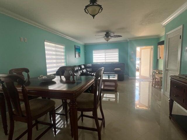 tiled dining room with ceiling fan and ornamental molding