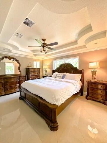 bedroom with crown molding, ceiling fan, and a tray ceiling