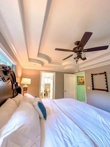 bedroom with ornamental molding, a raised ceiling, and ceiling fan