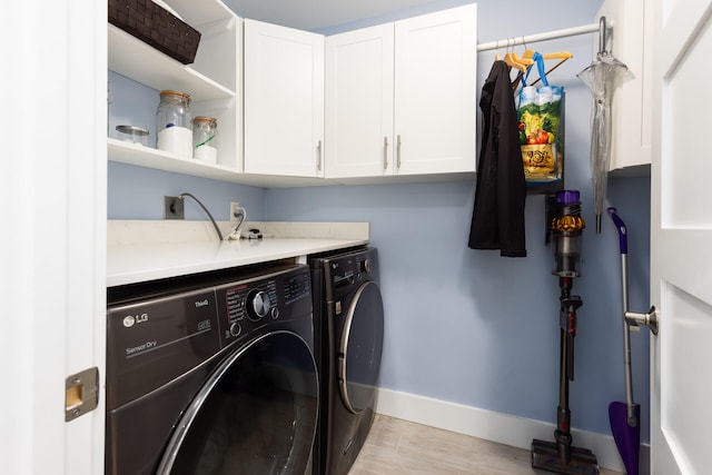 washroom with cabinets, washer and dryer, and light hardwood / wood-style floors