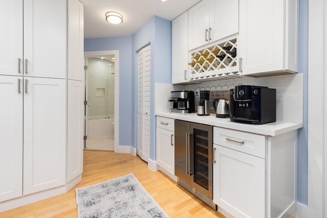 bar with white cabinetry, backsplash, wine cooler, and light hardwood / wood-style flooring