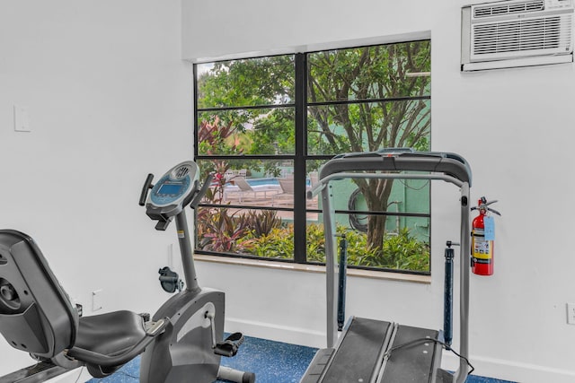 exercise room featuring a wall mounted air conditioner and plenty of natural light