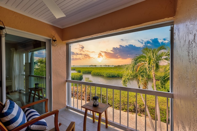 balcony at dusk featuring a water view