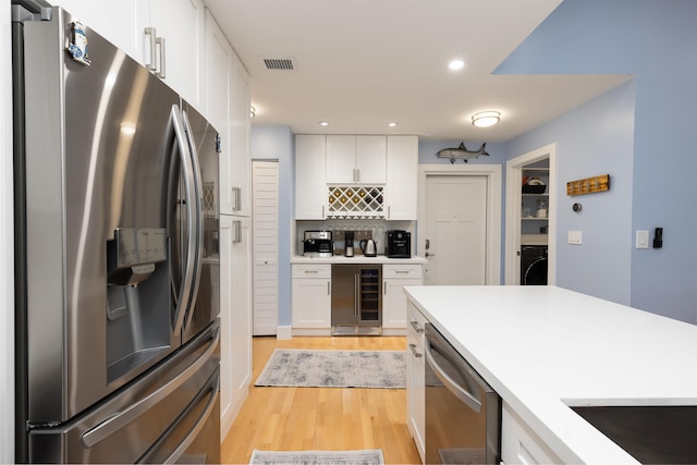 kitchen with white cabinetry, appliances with stainless steel finishes, tasteful backsplash, and wine cooler