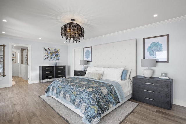 bedroom with ornamental molding, an inviting chandelier, and light hardwood / wood-style flooring