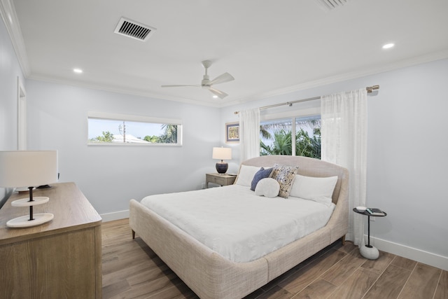 bedroom with hardwood / wood-style flooring, ornamental molding, ceiling fan, and multiple windows