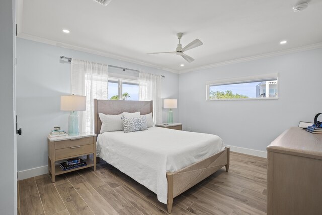 bedroom featuring multiple windows, ornamental molding, and light wood-type flooring