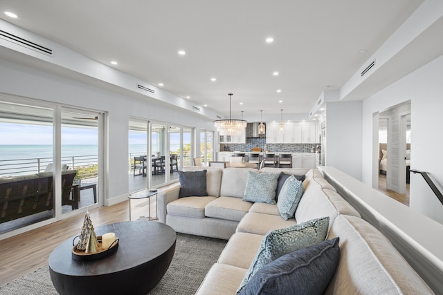 living room featuring a water view, an inviting chandelier, and light wood-type flooring