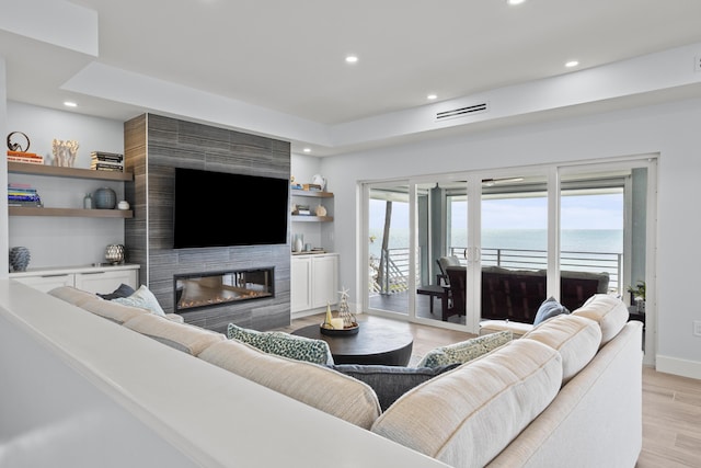 living room with plenty of natural light, light hardwood / wood-style floors, and a large fireplace