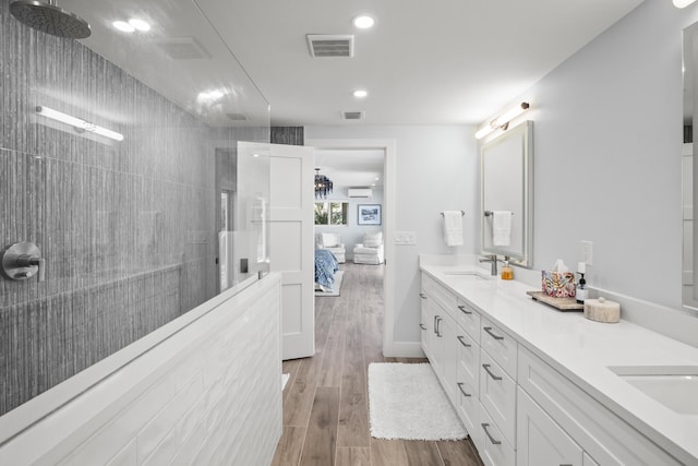 bathroom featuring vanity, wood-type flooring, and a tile shower