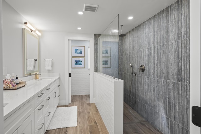 bathroom with vanity, hardwood / wood-style floors, and tiled shower