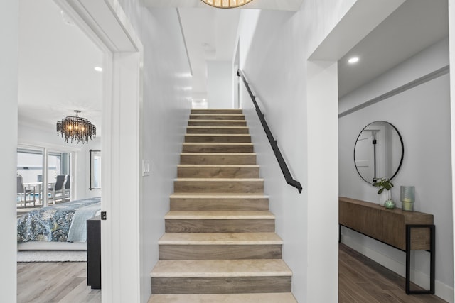 stairs featuring an inviting chandelier and wood-type flooring