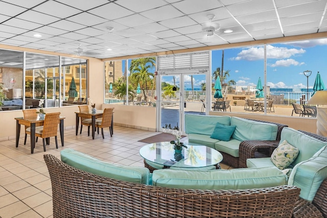 sunroom featuring french doors, a drop ceiling, a ceiling fan, and a city view