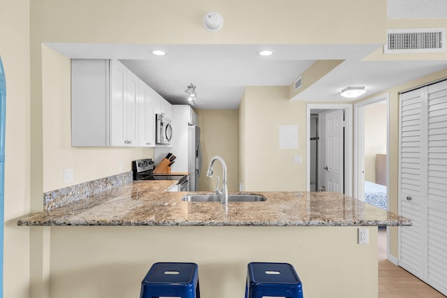 kitchen with a breakfast bar area, visible vents, appliances with stainless steel finishes, a sink, and a peninsula