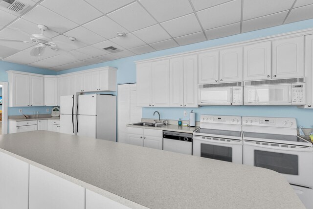 kitchen featuring white appliances, a sink, visible vents, and white cabinets