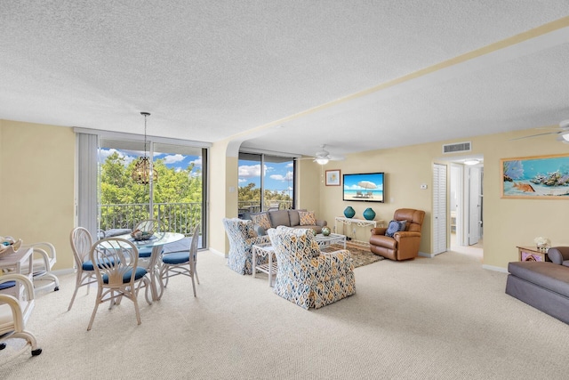 living area featuring light carpet, ceiling fan with notable chandelier, visible vents, and baseboards