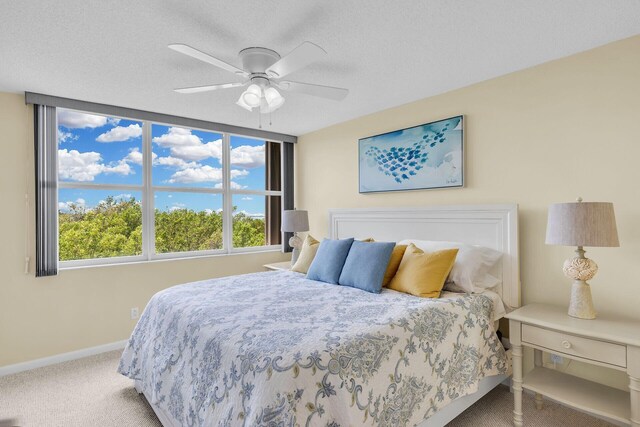 carpeted bedroom with a ceiling fan, baseboards, and a textured ceiling