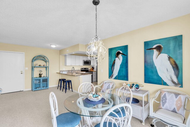 dining room featuring a textured ceiling, baseboards, a notable chandelier, and light colored carpet