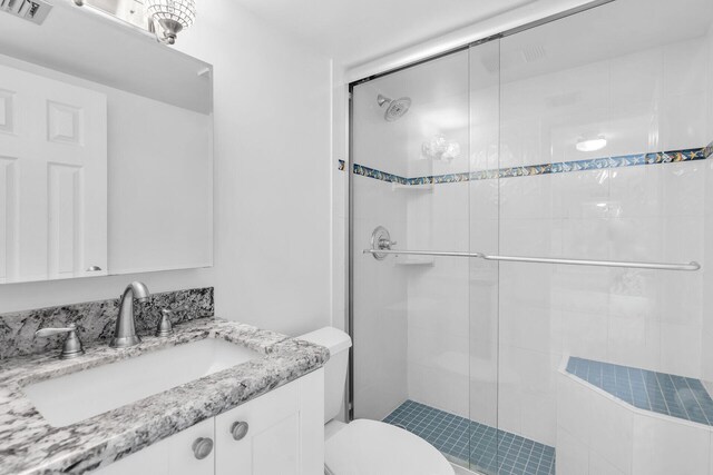 bathroom with toilet, a stall shower, vanity, and visible vents