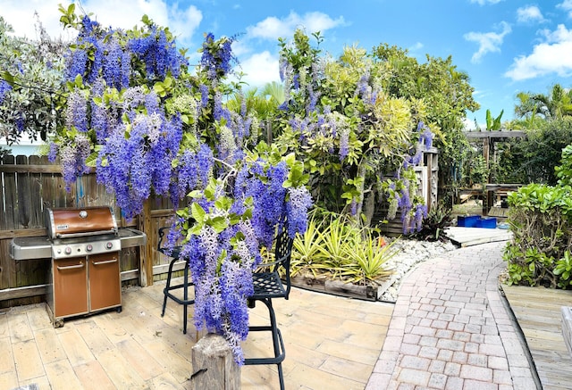 view of patio / terrace with grilling area, fence, and a deck