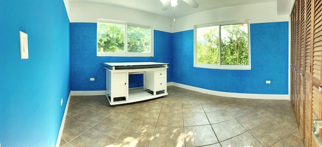 unfurnished office featuring a wealth of natural light, tile patterned flooring, and ceiling fan