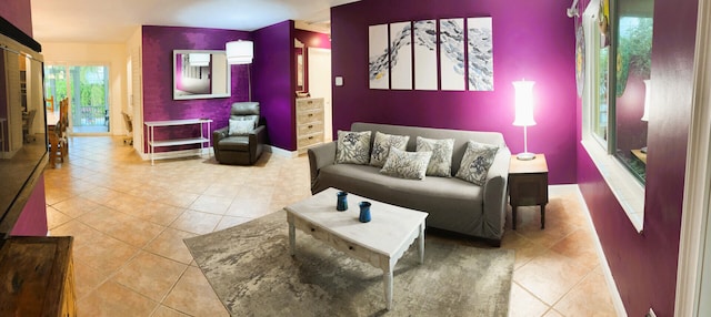 living room featuring tile patterned flooring, an accent wall, and baseboards