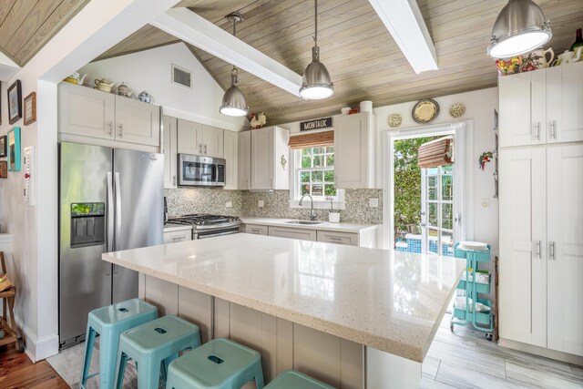 kitchen featuring appliances with stainless steel finishes, pendant lighting, sink, decorative backsplash, and a center island