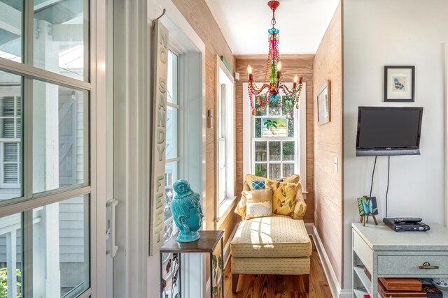 living area featuring hardwood / wood-style flooring, a notable chandelier, and wooden walls