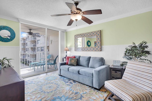 living room with ceiling fan, crown molding, expansive windows, and a textured ceiling