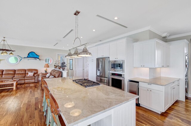 kitchen featuring stainless steel appliances, a kitchen island, pendant lighting, and white cabinets