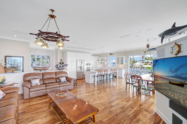 living room featuring crown molding, a healthy amount of sunlight, and light wood-type flooring