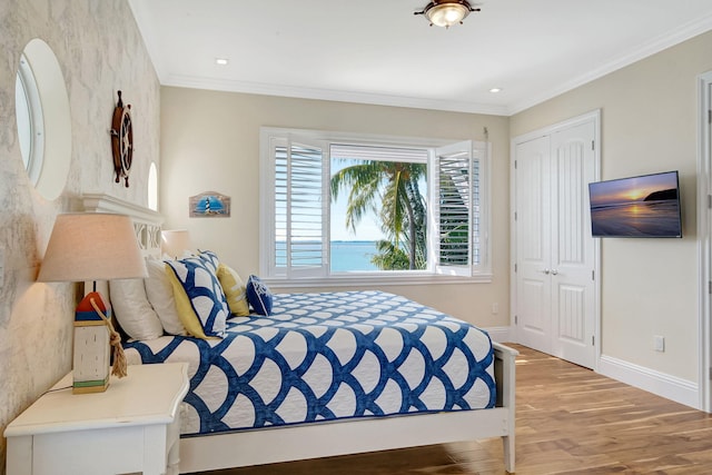 bedroom with hardwood / wood-style flooring, ornamental molding, and a closet