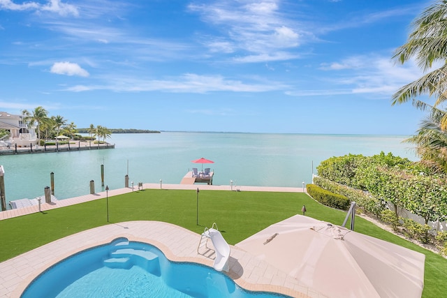 view of swimming pool with a water view, a yard, and a dock