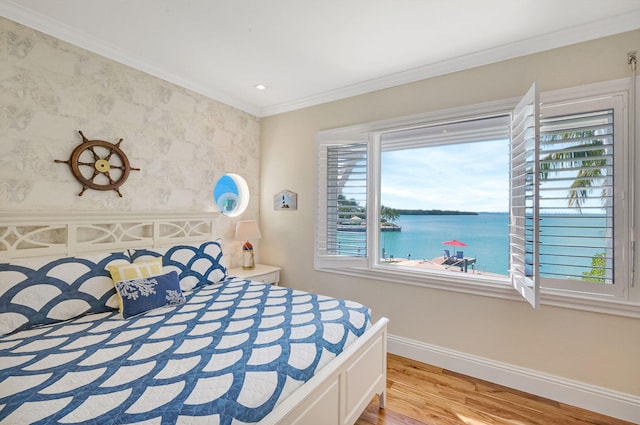 bedroom with light hardwood / wood-style flooring, ornamental molding, and a water view