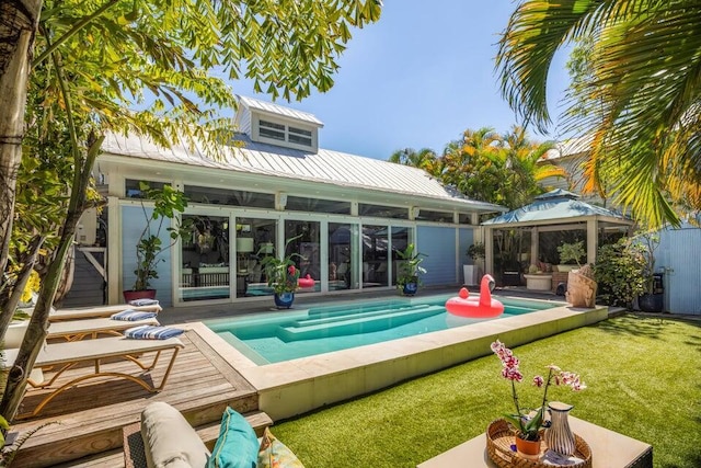 back of house at night with metal roof and an outdoor pool