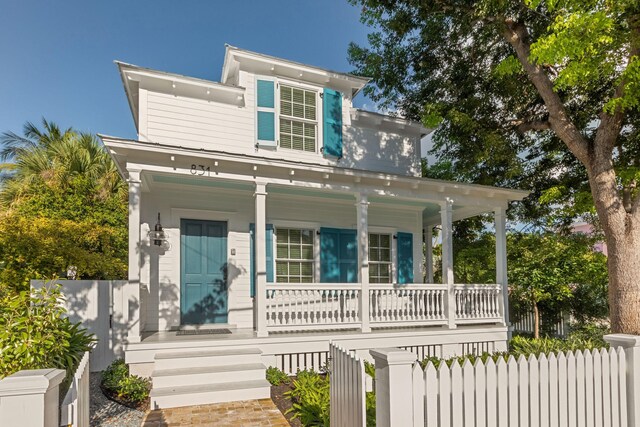 view of front of property with covered porch, fence, and stairs