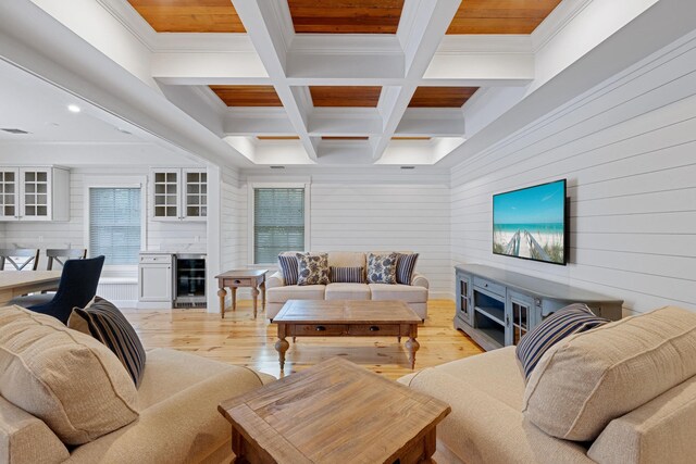 living area featuring wine cooler, beamed ceiling, light wood-style floors, ornamental molding, and wooden walls
