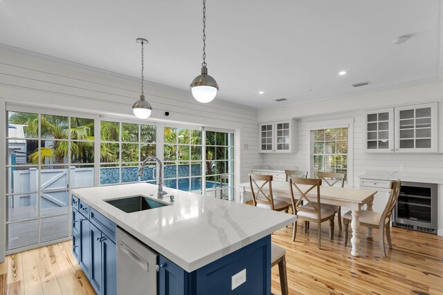 kitchen with wine cooler, a sink, blue cabinetry, stainless steel dishwasher, and light wood-type flooring