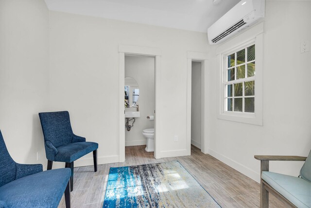living area featuring a wall mounted AC, wood finished floors, and baseboards