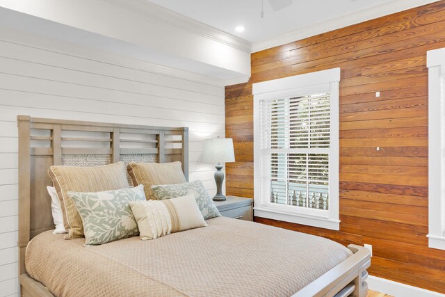 bedroom with wood walls, crown molding, and a ceiling fan
