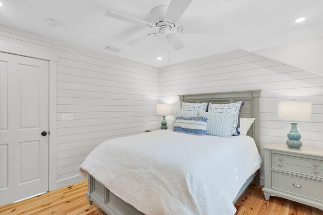 bedroom with light wood-style flooring, wooden walls, recessed lighting, and a ceiling fan