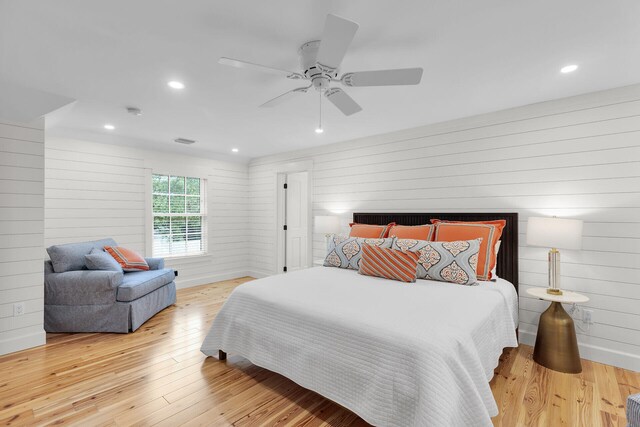 bedroom featuring hardwood / wood-style floors, wooden walls, a ceiling fan, and recessed lighting