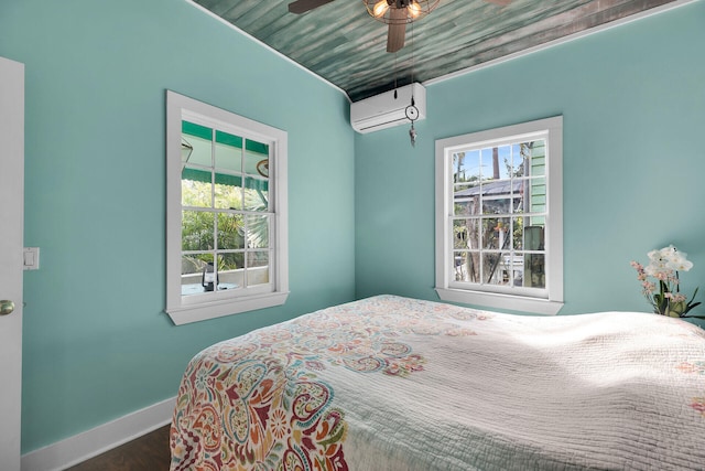 bedroom featuring a wall mounted AC, wood finished floors, and baseboards