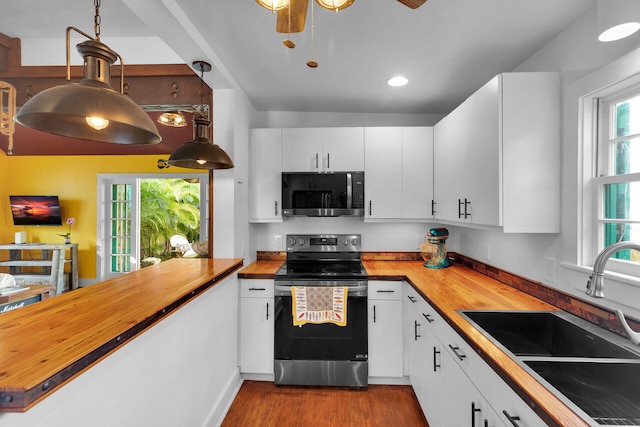 kitchen featuring dark wood-style floors, butcher block countertops, appliances with stainless steel finishes, and a sink