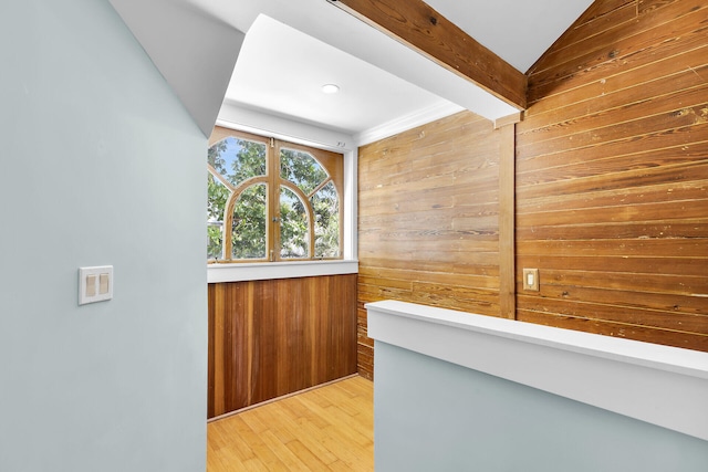 interior space with vaulted ceiling with beams, wooden walls, and light wood-type flooring