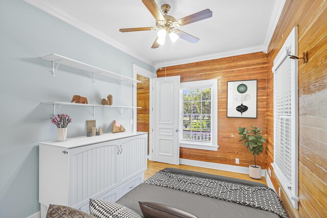 interior space featuring crown molding, wood walls, ceiling fan, and light hardwood / wood-style flooring