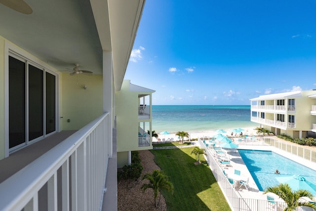 balcony with a beach view, a water view, and a ceiling fan